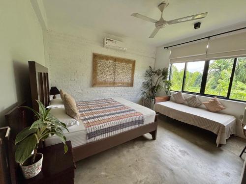 a bedroom with two beds and a couch and windows at Rai Villa Colombo in Colombo