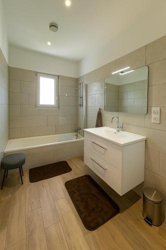 une salle de bain avec un lavabo, une baignoire et un miroir dans l'établissement Jolie villa avec piscine, à Monticello