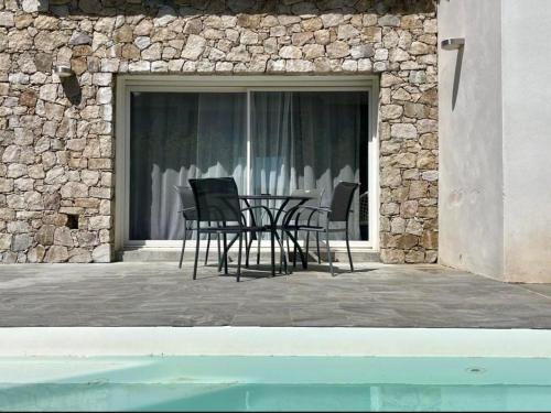 a patio with chairs and a table in front of a building at Jolie villa avec piscine in Monticello