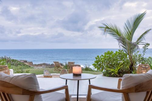 a patio with chairs and a table and the ocean at Sala Beach House in Ballito