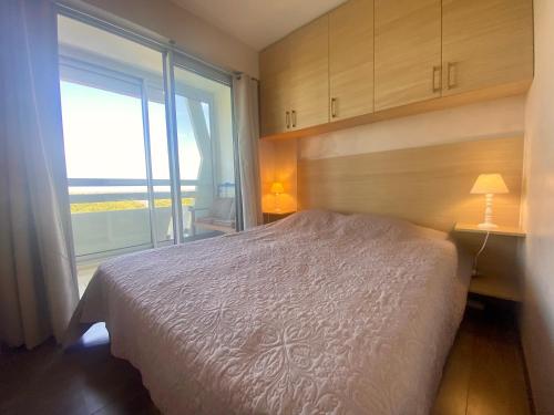 une chambre avec un lit et une grande fenêtre dans l'établissement LA GRANDE MOTTE – T2 VUE MER ET PINÈDE – 4 PERSONNES – PARKING PRIVATIF, à La Grande Motte