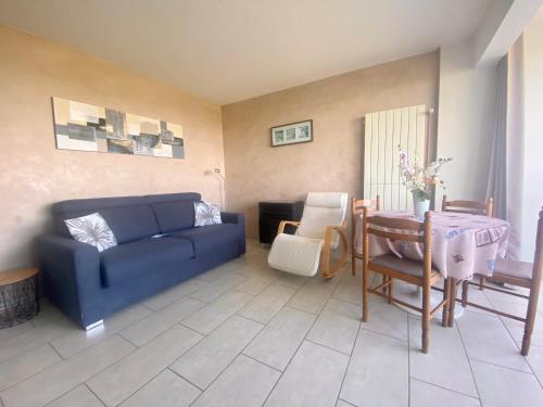 un salon avec un canapé bleu et une table dans l'établissement LA GRANDE MOTTE – T2 VUE MER ET PINÈDE – 4 PERSONNES – PARKING PRIVATIF, à La Grande Motte