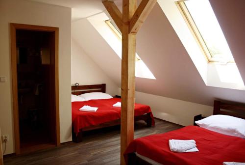 a attic bedroom with two beds with red sheets at Penzion Starovice in Starovice