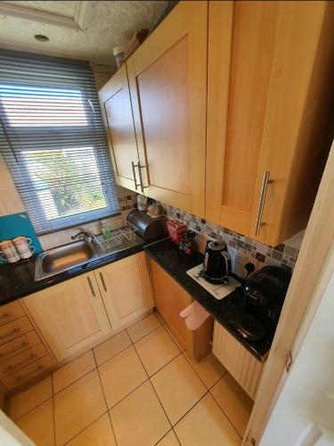 a kitchen with wooden cabinets and a black counter top at Animal friendly Sea 2 mins away in Trusthorpe