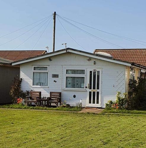 a white house with a bench in front of it at Animal friendly Sea 2 mins away in Trusthorpe