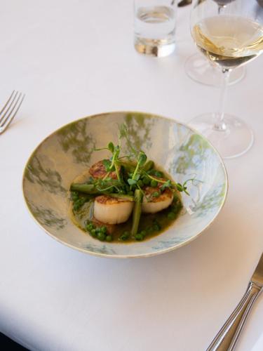 a plate of food on a table with a wine glass at Hostal Empúries in L'Escala