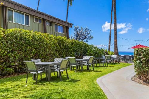 a row of tables and chairs on the grass near a building at Beachfront Condo in Kihei in Kihei