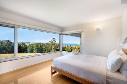 a bedroom with a bed and large windows at Marion Bay House, Luxury Retreat in Bream Creek