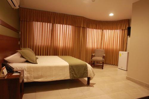 a hotel room with a bed and a chair at Hotel Puerto Banana in El Guabo