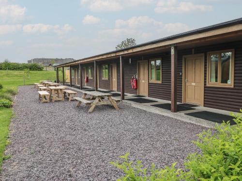 a row of wooden lodges with benches and tables at Chestnut in Cowbridge