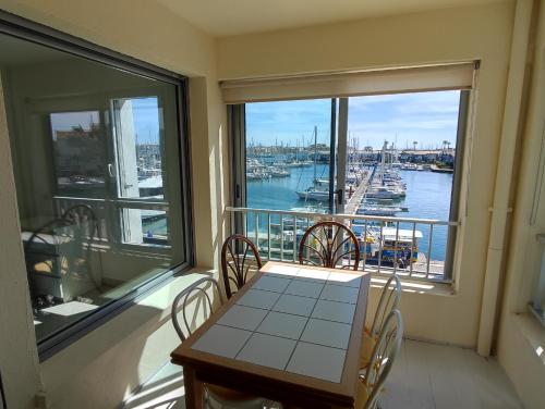 カップ・ダグドにあるCap d'Agde F3 belle vue port avec Garage Piscine Climatisationの港の景色を望むバルコニー(テーブル、椅子付)