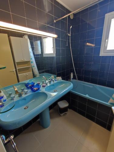 La salle de bains bleue est pourvue d'un lavabo et d'une baignoire. dans l'établissement Cap d'Agde F3 belle vue port avec Garage Piscine Climatisation, au Cap d'Agde