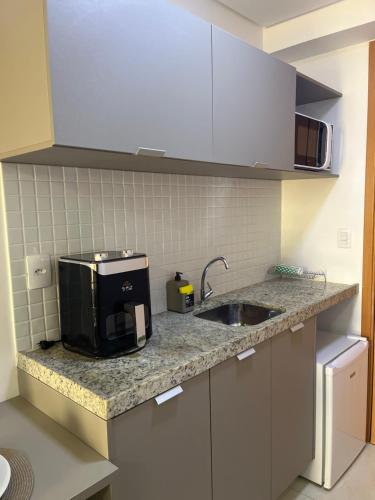 a kitchen with a sink and a microwave at Manaíra Apart Hotel in João Pessoa