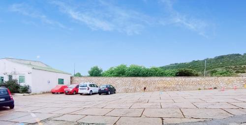 a parking lot with cars parked next to a brick wall at Hotel Calamosca in Cagliari