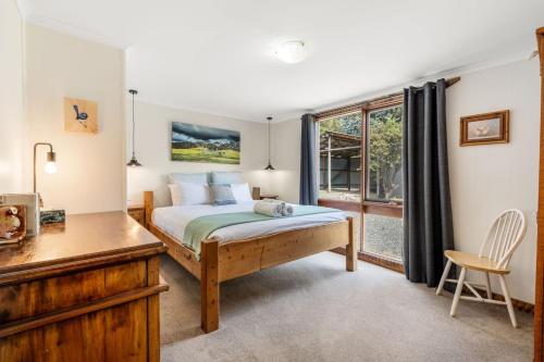 una camera da letto con un letto, una scrivania e una finestra di Secluded Huon Valley Lodge with Hot Tub and Cottage a Lymington