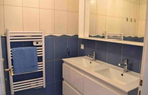 baño azul y blanco con lavabo y espejo en Appartement Agate Vals les bains, en Vals-les-Bains