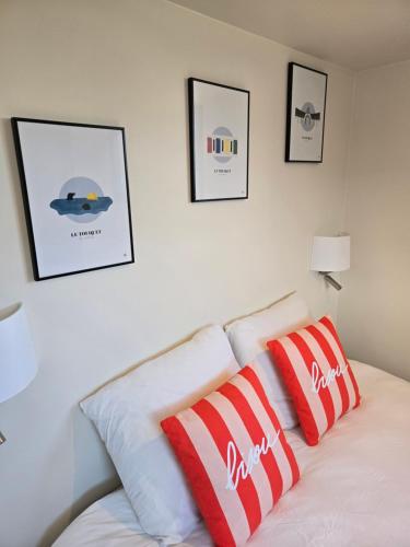 a white bed with red and white pillows on it at Chambre Cosy Indépendante aux pieds des dunes in Merlimont
