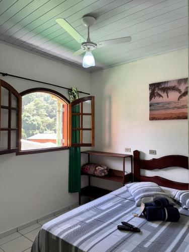 a bedroom with a bed with a ceiling fan and a window at Pouso da Celeste - Trindade in Trindade