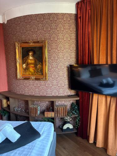 a room with a tv and a painting on the wall at Cameo Boutique Hotell in Ystad