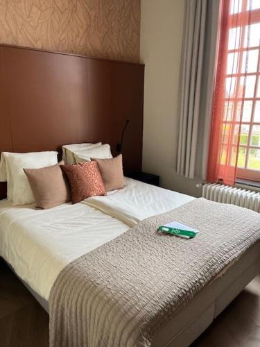 a bedroom with a bed with a green book on it at Amaryllis Hotel Veurne in Veurne