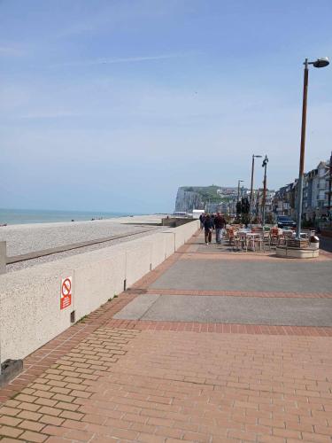 a sidewalk next to the beach with people walking on it at Face à la mer by Corinne in Mers-les-Bains