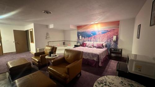 a hotel room with a bed and a couch and chairs at Chesaning INN & Suites in Chesaning