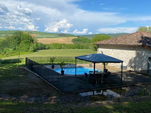- une piscine avec un parasol et une maison dans l'établissement Maison charmante à Puygaillard-de-Quercy avec piscine privée, à Puygaillard-de-Quercy