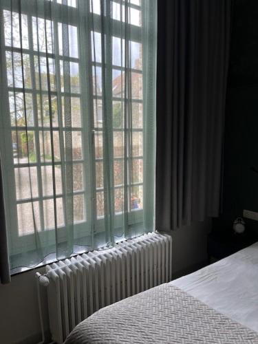 a bedroom with a bed and a window with a radiator at Amaryllis Hotel Veurne in Veurne