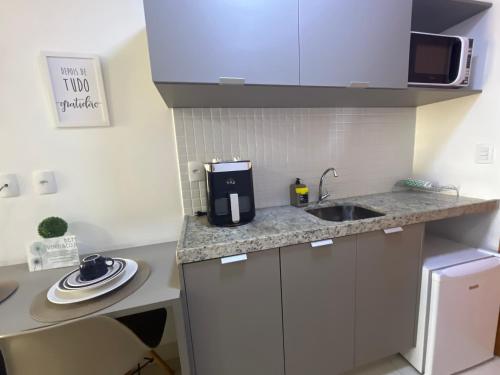 a small kitchen with a sink and a microwave at Manaíra Apart Hotel in João Pessoa