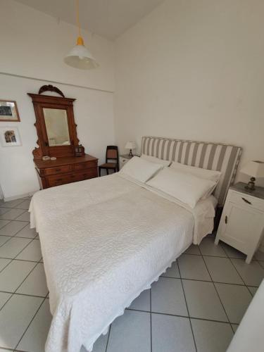 a bedroom with a white bed and a wooden dresser at Home sweet home in Ischia