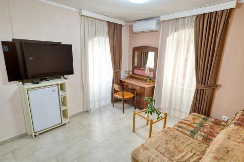 a living room with a couch and a desk and a television at Hotel Rendez Vous in Kotor