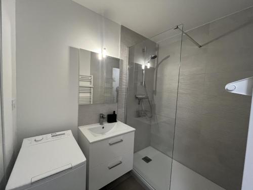 une salle de bain blanche avec un lavabo et une douche dans l'établissement LA MIOUGRANO T3 etat neuf 5-6p, climatise, 300m de la, à Fréjus
