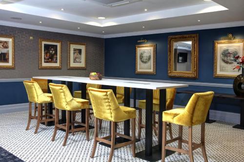 a bar with yellow chairs and a table in a room at Crowne Plaza East Midlands Airport by IHG in Derby