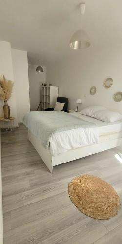 - une chambre blanche avec un grand lit et un tapis dans l'établissement Chez Marie et Seb, à Pomérols
