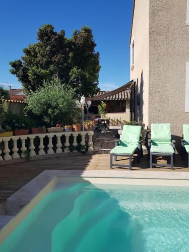 - une piscine avec 2 chaises à côté d'un bâtiment dans l'établissement Villa piscine privée, à Capestang
