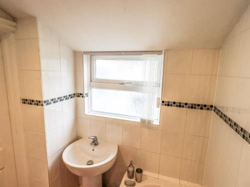 a bathroom with a sink and a toilet and a window at Violey Cottage in Maryport
