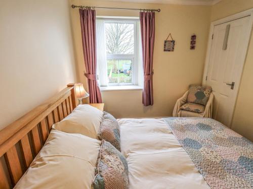a bedroom with a bed and a window and a chair at Violey Cottage in Maryport