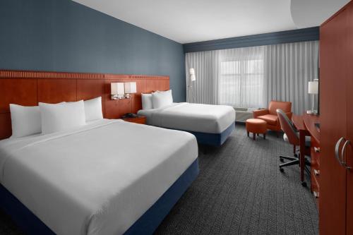 a hotel room with two beds and a desk at Courtyard by Marriott Santa Clarita Valencia in Valencia