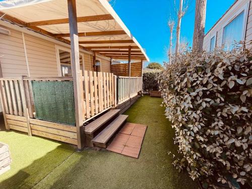 une maison avec une terrasse couverte dotée d'un banc et d'une clôture dans l'établissement Mobil Home Jasmins 1, à Valras-Plage