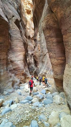 a group of people walking through a slot canyon at Dana bedouin Sky in Dana