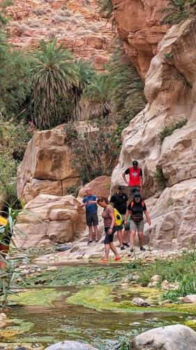 a group of people walking down a rocky trail at Dana bedouin Sky in Dana