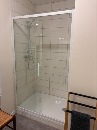 une douche avec une porte vitrée dans une salle de bain dans l'établissement Bel appart neuf 6 pers Ecueille Centre, à Écueillé