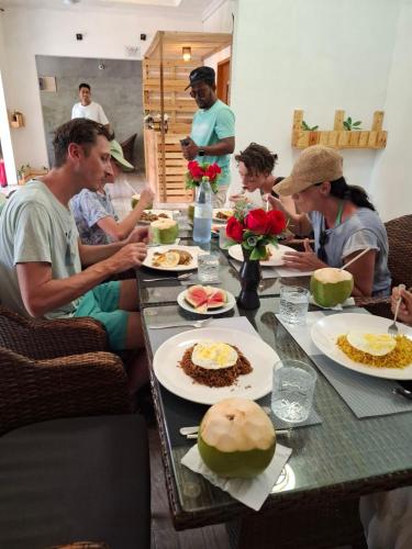 a group of people sitting around a table with food at Dhontakuru Guest House in Ariyaddu