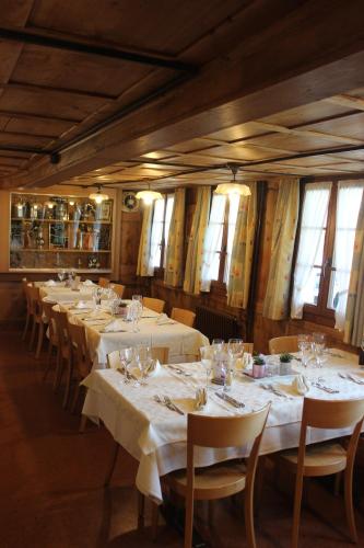 a dining room with white tables and chairs and windows at Landgasthof Grossteil in Giswil