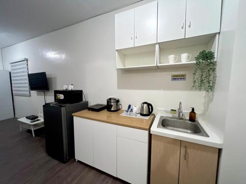a small kitchen with a sink and a refrigerator at Amaia step parkway nuvali studio in Calamba