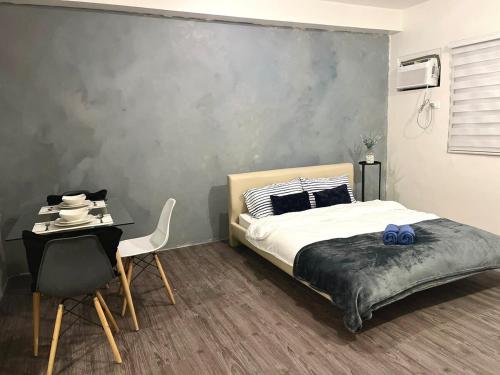 a bedroom with a bed and a table and a chair at Amaia step parkway nuvali studio in Calamba