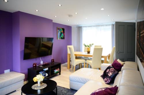 a living room with purple walls and a white couch at Strelley house 2 , Perfect for business trip & Families holiday or working proffesionals-5 min from M1 J25 , 500MB Wi-Fi , Netflix , Fully equiped kitchen , Asda supermarket 5 min walk , Free Secure parking with CCTV ,available monthly deals in Nottingham