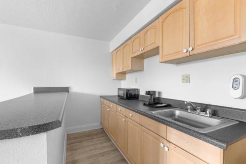 a kitchen with wooden cabinets and a sink at Casa Del Mar Hotel in Norfolk