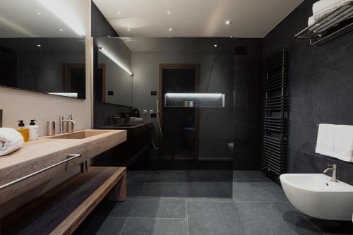 a bathroom with a sink and a toilet and a tub at Mostesi Dolomites Spa Hotel in Auronzo di Cadore