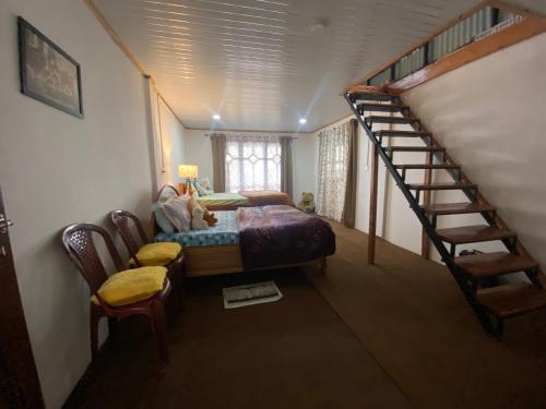 a bedroom with a bed and a spiral staircase at Máple farmstay in Darjeeling